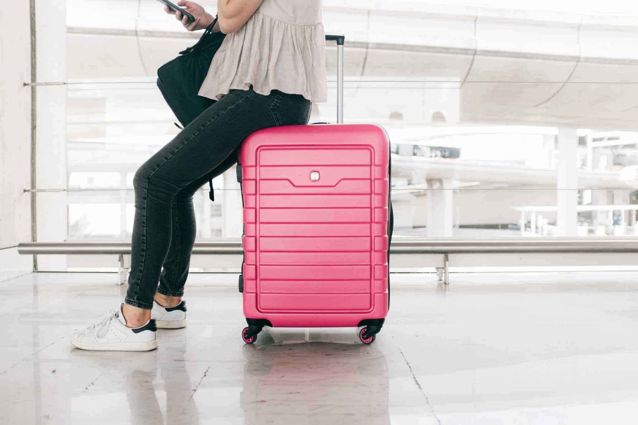 Woman sitting on her luggage while waiting in the airport.