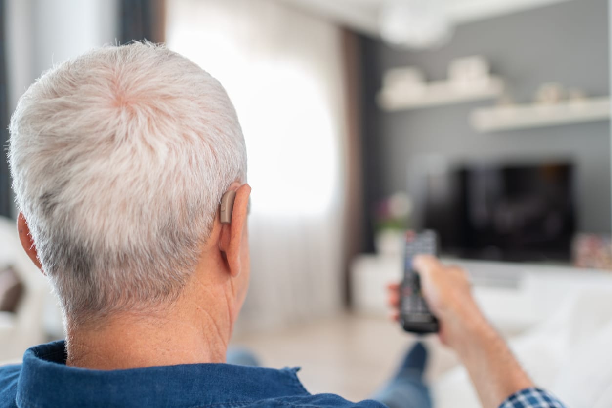 Man watches TV with hearing aid