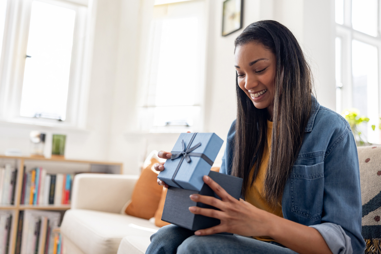 Woman smiling while opening a present at home