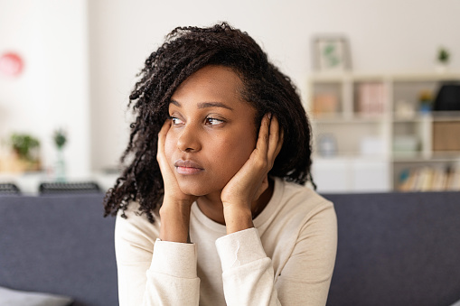 Woman sitting on her couch looking blue.