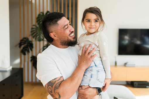 Dad holding his smiling daughter.