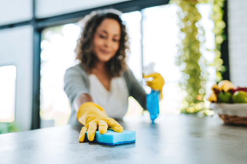 Woman cleaning a counter with a sponge.
