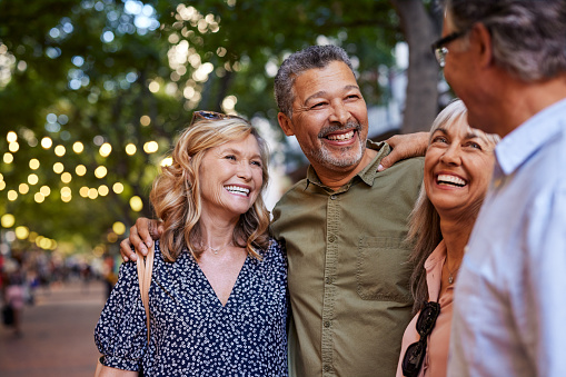 Older men and laughing women chatting together during a walk.