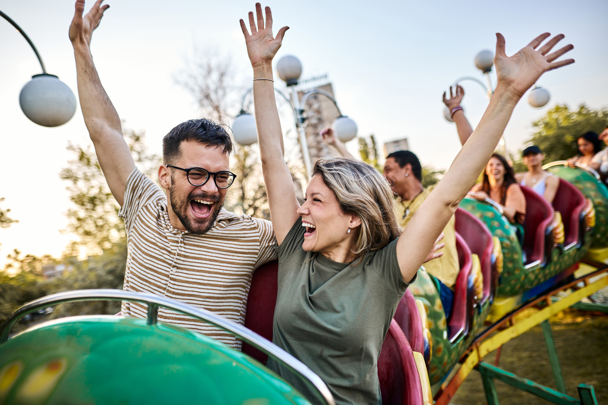 A couple with their hands up on an amusement park ride.