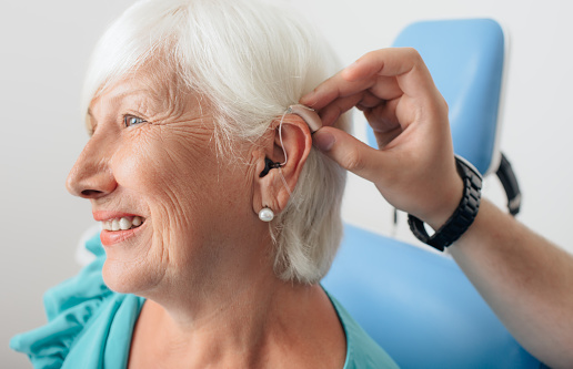 Doctor helping a patient with her hearing aid , close-up.